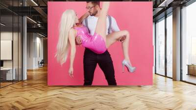 Funny man holds and hug woman in arms. Couple in sexy dolls style. Handsome elegant young man holding his girlfriend in arms. Wall mural