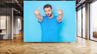 Gesture pointing finger at you. The point you. Happy handsome man pointing finger you away, isolated blue background. Excited man pointing a you great idea. Guy in blue t-shirt pointing finger you. Wall mural