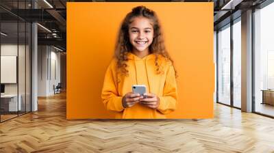 girl with phone on orange background. Wall mural