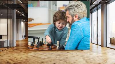 Handsome teacher giving private lessons chess to preschool boy. Father teaching his son to play chess. Intelligent kids. Wall mural