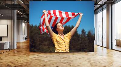 Happy 4th of July! Independence Day celebrating. Patriotic woman hold wrapped in american national flag waving on wind and walking on the field. Stars and stripes. Freedom concept.
 Wall mural