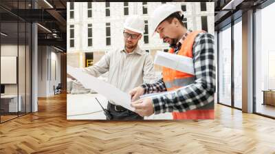 Male architect and developer with blueprints  discussing architect project at construction site. Wall mural