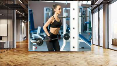 Young woman in a gym making exercises with a barbell Wall mural