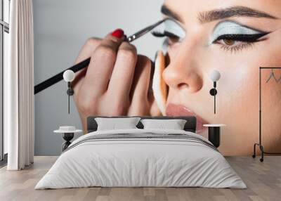 Makeup artist applies eye shadow. Hand of visagiste, painting cosmetics of young beauty model girl. Cosmetology, beauty and spa. Portrait of beauty model with make up on beauty face. Wall mural