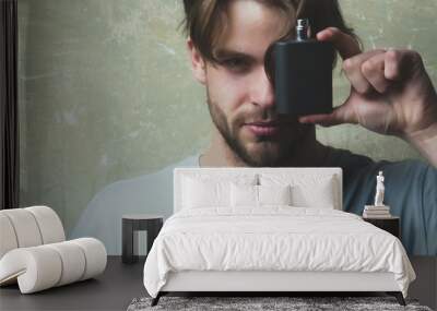 man covering eye with black perfume bottle Wall mural