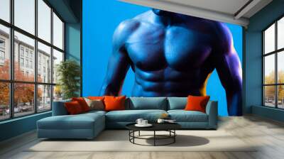 Muscular model sports young man on blue dark background. Fashion portrait of strong brutal guy with a modern trendy blue color. Sexy bare torso. Sport workout bodybuilding concep. Wall mural