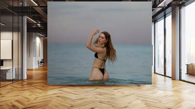 Photo of beautiful sexy woman in bikini relaxing on summer beach. Young sexy woman in bikini posing in ocean water. Beautiful tall slim female model in the sea. Wall mural