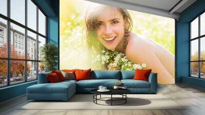 Portrait of a beautiful young girl in the spring with wildflowers. Happy summer face of young woman in green nature field. Wall mural