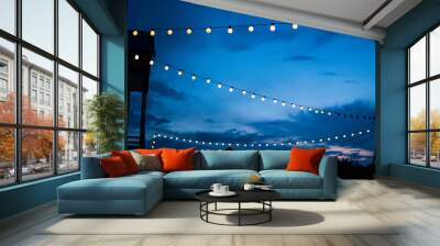 Row of hanging summer terrace lights during evening, small outdoor light bulbs. Wall mural