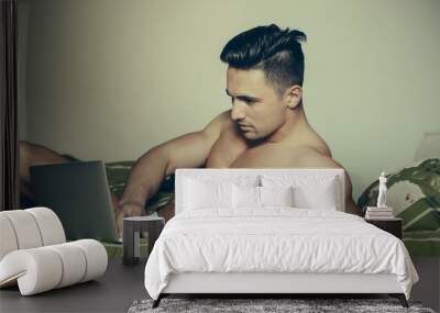 Sexy man in bed with laptop Wall mural