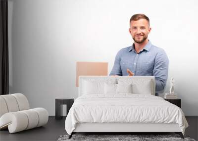 Casual young man holding a box isolated on a white background Wall mural