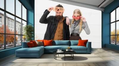 Stylish couple in huge orange glasses posing in studio. Man with nice beard and mustache hugging blond attractive girl. Fashion shooting Wall mural