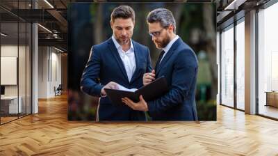 Two businessmen discussing outdoor. Two business people talk project strategy. Two american businessmen in suits walk outdoors in the city and discuss business. Wall mural