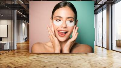 Under eye patches for dark circles and puffiness. Taking care of her skin. Pretty woman using eye patches spending time at home. Daily pampering routine. Modern cosmetics. Eye patches concept Wall mural