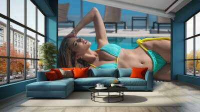 Woman posing by the pool. Summer vacation. Sexy woman in swimwear bikini relaxing in swimming pool spa. Vacation at luxury resort. Sexy girl in pool, poolside, beach vacation, swimming in the water. Wall mural