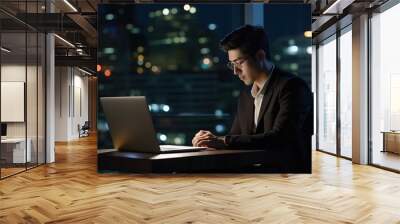 Young busy Asian business man executive working on laptop at night in dark corporate office. Wall mural