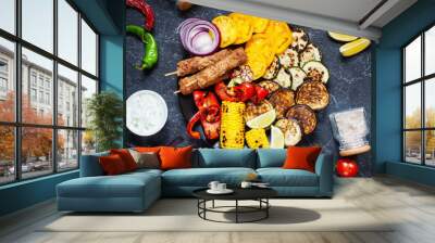 Assorted delicious grilled vegetables and meat on a dark stone background. Summer food Wall mural