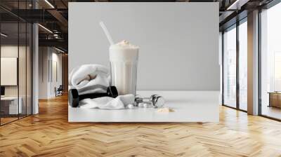 Vanilla protein shake with white glass and straw dumbbell towel and fitness accessories on a white bar table Wall mural