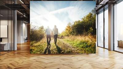 A young couple walking outdoors holding hands. Wall mural