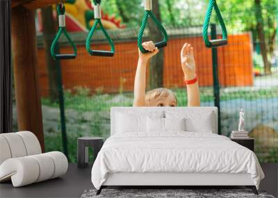 Cute boy playing on monkey bars. Kids sport outdoors. Summer vacation, camp and leisure. Wall mural