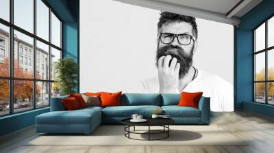 Pensive man touching his beard on white wall. Handsome man in glasses thinks. Emotional bearded guy has a doubt. Human face expressions, emotions, feelings, body language Wall mural