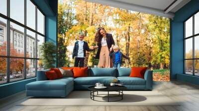 Stylish family on a walk. Mother with two children having fun outdoors in cool autumn weather. Fashion, lifestyle and family. Wall mural