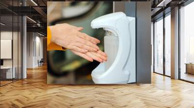 Washing hands using automatic sanitizer dispenser. Automatic sanitizer dispenser at supermarket. Coronavirus prevention. Wall mural