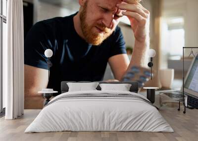 Bearded man holding medication packaging at home Wall mural