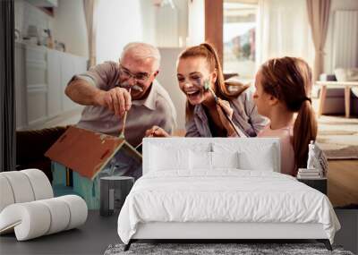 Grandfather, Mother, and Daughter Painting Small House Together at Home Wall mural