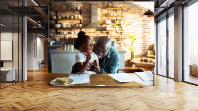 Grandfather laughing with granddaughter in kitchen Wall mural