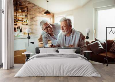 Senior couple using laptop at home Wall mural