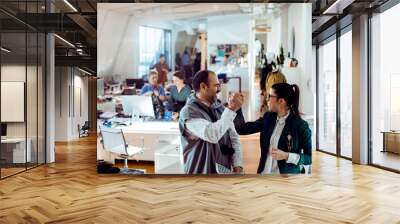 Two fashion designers celebrating success with a high-five in a creative studio Wall mural