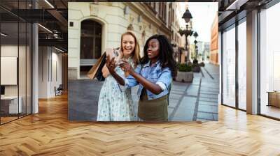 Two women taking a selfie together on a sunny city street Wall mural