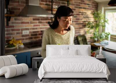 Woman taking vegetables out of cardboard box in kitchen at home Wall mural