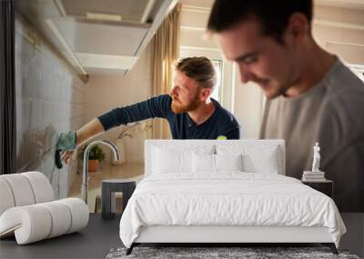 Young male gay couple cleaning their kitchen together Wall mural