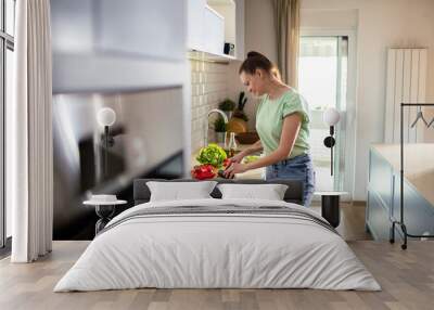 Young woman preparing healthy vegetarian meal in kitchen Wall mural