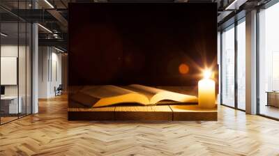 a bible on the table in the light of a candle Wall mural