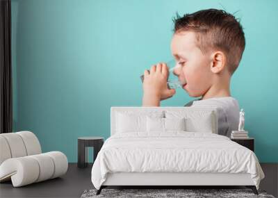 child drinks water on a turquoise background Wall mural