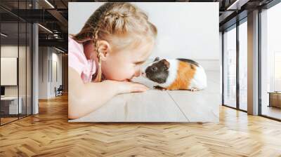 girl holding a guinea pig in her arms, on a black background. a lot of joy and fun Wall mural