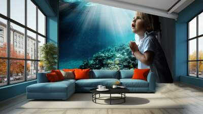 the child looks out the window on fish and the coral bottom in the aquarium Wall mural