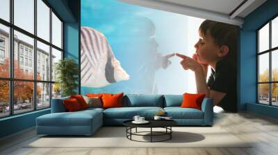 the child looks out the window on fish and the coral bottom in the aquarium Wall mural