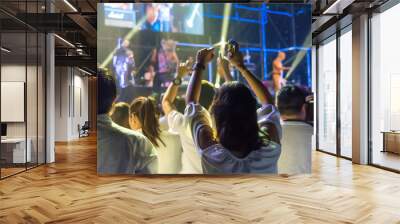 Crowd of hands up concert stage lights enjoying concert, and people fan audience silhouette raising hands in festival music rear view with spotlight glowing effect, blurred Wall mural