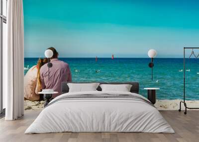 couple sitting on beach rear view Wall mural