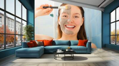 Woman applying mud facial mask Wall mural