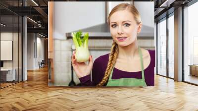 Woman in kitchen holds raw fennel bulb vegetable Wall mural