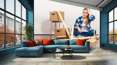 Woman moving into apartment assembly furniture. Wall mural