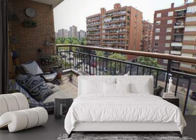 Cozy urban balcony with comfortable seating, potted plants, and city skyline views creating a relaxing and inviting outdoor space Wall mural