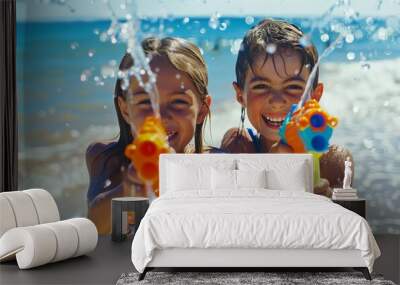 Two children having fun, shooting water with water guns in the sea, splashing around Wall mural