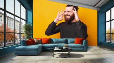 A photo of a young bearded man having a head ache . Wall mural