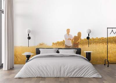 A young happy couple is dancing playful on a sunny field. Wall mural